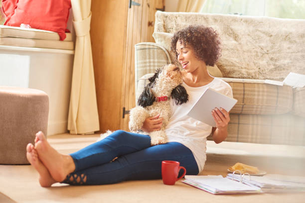 Femme assise sur le sol qui lit des documents avec son chien dans les bras