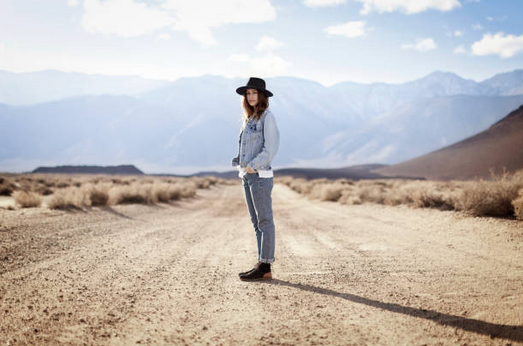 Femme habillée en look denim au milieu d'une route déserte des Etats-Unis