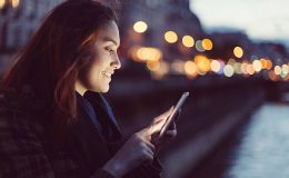 Femme qui envoie un message sur son smartphone à la tombée de la nuit