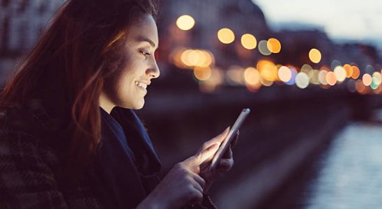 Femme qui envoie un message sur son smartphone à la tombée de la nuit