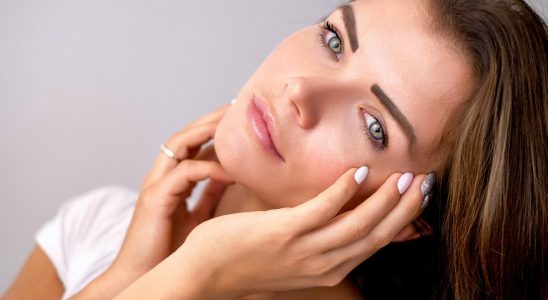 Belle femme brune aux yeux bleus qui tient sa tête penchée entre ses mains