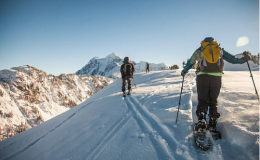 personnes qui font une randonnée en raquettes dans la neige