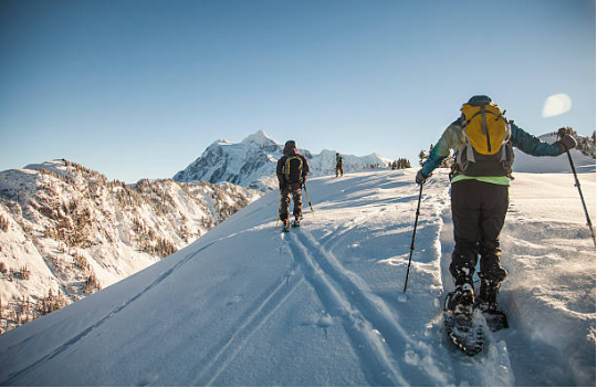 personnes qui font une randonnée en raquettes dans la neige